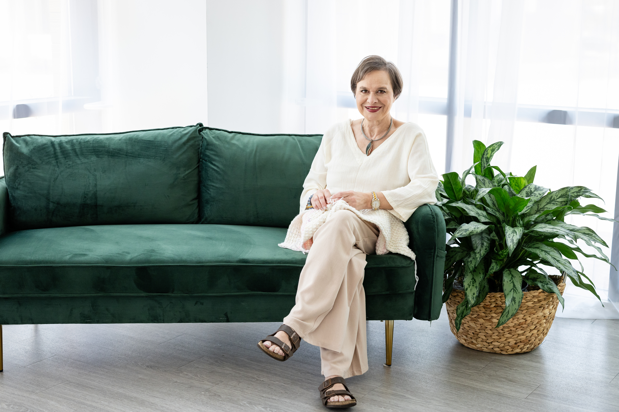 Luiza sitting on couch holding crochet project.